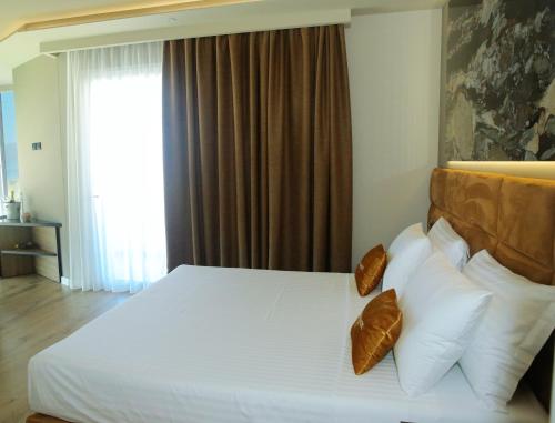 a bedroom with a bed with white pillows and a window at Kraal Hotel Vlore in Vlorë