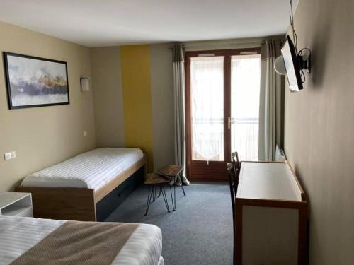 Habitación de hotel con 2 camas y ventana en Logis Hotel Restaurant des Voyageurs en Le Malzieu-Ville