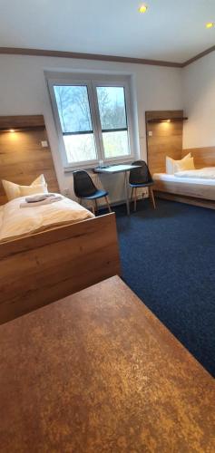 a hotel room with two beds and a table and chairs at Hotel-Restaurant Elsterblick in Elsteraue