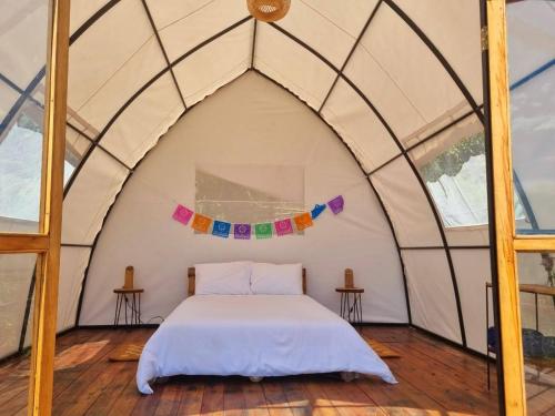 1 dormitorio en una tienda abovedada con 1 cama en Ecoglamping Reserva Natural Paraíso Andino, en La Vega