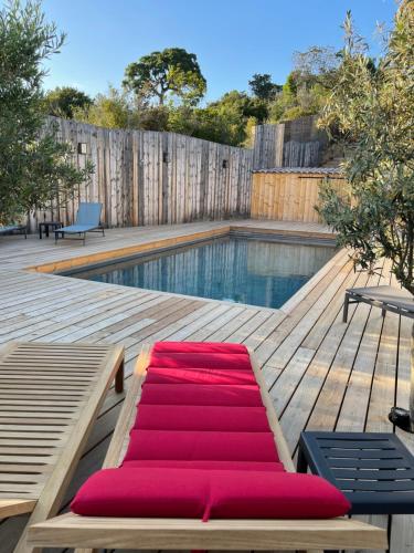 - une piscine avec une chaise longue rouge sur une terrasse en bois dans l'établissement Senteurs du Maquis, à Porticcio