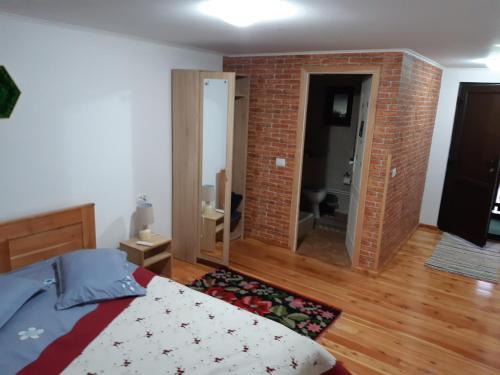 a bedroom with a bed and a brick wall at CASA DINTRE PINI in Păltinoasa