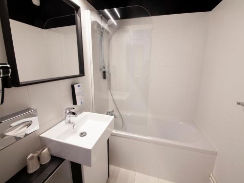 a white bathroom with a sink and a shower at Kyriad Hotel Clermont Ferrand Centre in Clermont-Ferrand