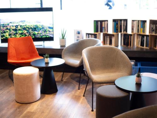 un groupe de chaises et de tables dans une bibliothèque dans l'établissement Kyriad Hotel Clermont Ferrand Centre, à Clermont-Ferrand