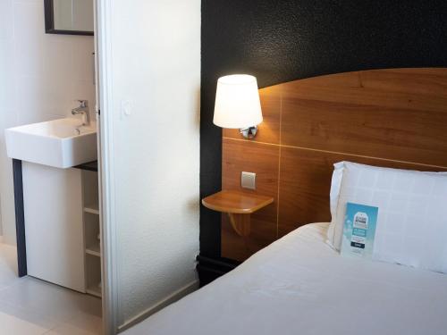 a bedroom with a bed and a sink and a lamp at Kyriad Hotel Clermont Ferrand Centre in Clermont-Ferrand