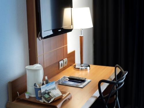 a desk in a hotel room with a lamp and a lamp at Kyriad Hotel Clermont Ferrand Centre in Clermont-Ferrand