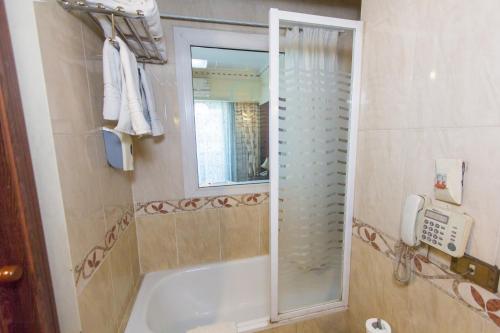 a bathroom with a tub and a shower with a phone at Philae Hotel Aswan in Aswan