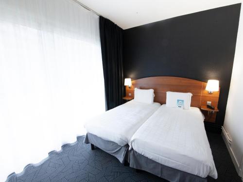 a hotel room with a large bed with white sheets at Kyriad Hotel Clermont Ferrand Centre in Clermont-Ferrand