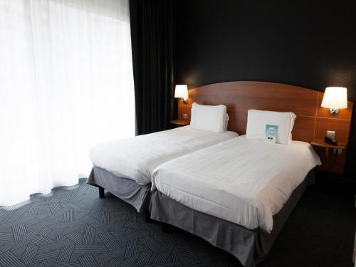 a hotel room with a large bed with white sheets at Kyriad Hotel Clermont Ferrand Centre in Clermont-Ferrand
