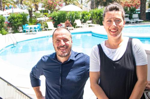a man and a woman standing next to a swimming pool at International Hotel & Suite in San Benedetto del Tronto