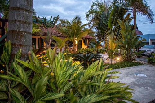 a house with palm trees and plants in front of it at Canto das Ondas Apart Studios in São Francisco do Sul