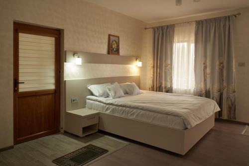 Un dormitorio con una cama grande y una ventana en Pensiunea Rares en Tălpăşeşti