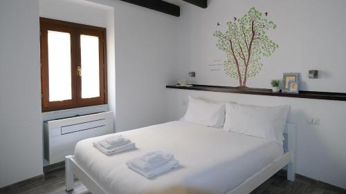 a white bedroom with a bed with towels on it at Welcomely - Santa Chiara in Alghero
