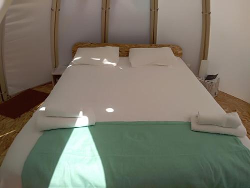 a white bed with a green blanket on it at Solmeco Park in Aldeia do Meco