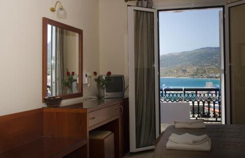 a bedroom with a mirror and a dresser with a large window at Hotel El Greco in Sitia