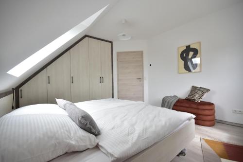 a bedroom with a large white bed and a staircase at Ostseehaus Boje in Krummin