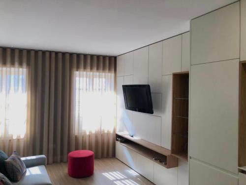 a living room with a tv and a red stool at Vila do Conde - Os Maias in Vila do Conde
