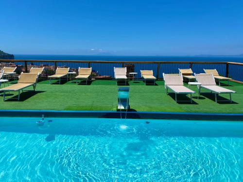 una piscina con sillas y el océano en el fondo en Corte Degli Ulivi Resort en Vico Equense