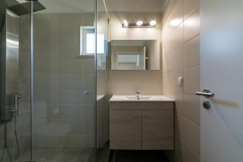 a bathroom with a sink and a glass shower at Villa Macuti by SAPvillas in Vilamoura