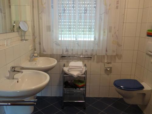 ein Bad mit 2 Waschbecken, einem WC und einem Fenster in der Unterkunft Villa Sonnenhof in Bad Steben