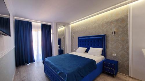 um quarto com uma cama azul e uma cabeceira azul em Grand Bahia Relaxury em Costinesti