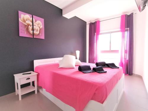 una camera con un letto rosa con una coperta rosa di Paraiso Sol Rocha Luxurious beach apartment a Portimão