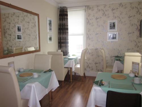 un restaurante con mesas, sillas y espejo en The Old Town Bed and Breakfast, en Hastings