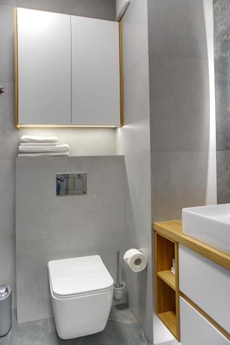 a bathroom with a white toilet and a sink at Essence Apartments Topaz in Poznań