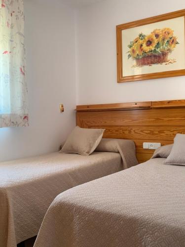 duas camas num quarto com uma fotografia na parede em Apartamentos La Proa em Torremolinos
