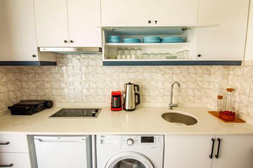 a kitchen with a sink and a washing machine at Granda Lambuka Apart in Kas