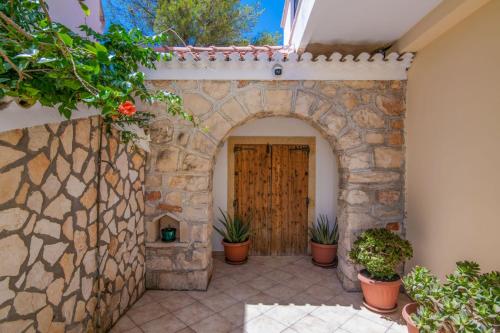 an entrance to a house with an arch and potted plants at SunBliss Studios & Apartments in Alykes