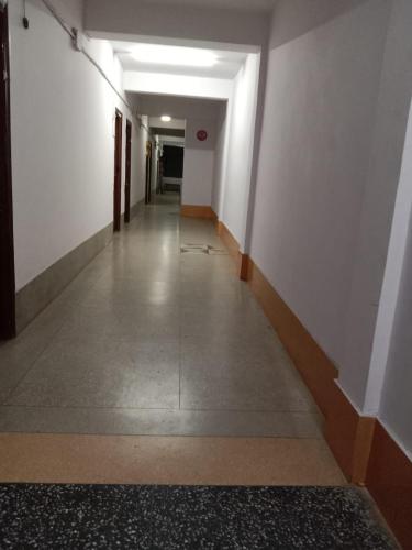 un pasillo vacío con paredes blancas y un pasillo largo en Hotel New Eastern, en Bokāro