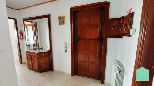 a bathroom with a wooden door and a sink at Casa Lena - Sítio da Nazaré in Nazaré