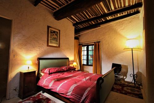 Schlafzimmer mit einem Bett mit roter Bettwäsche und einem Fenster in der Unterkunft Traditional Provencal Stone House in Entrecasteaux