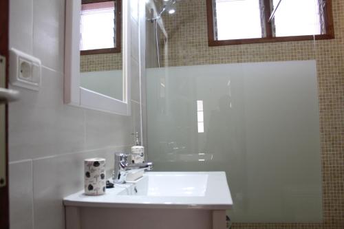 Baño blanco con lavabo y espejo en Casa Lulu en Tijarafe