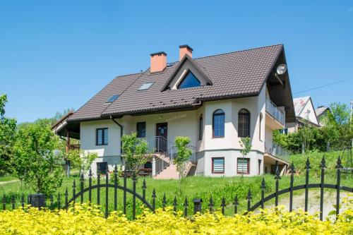 a white house with a black roof at HELENOWO in Lutowiska