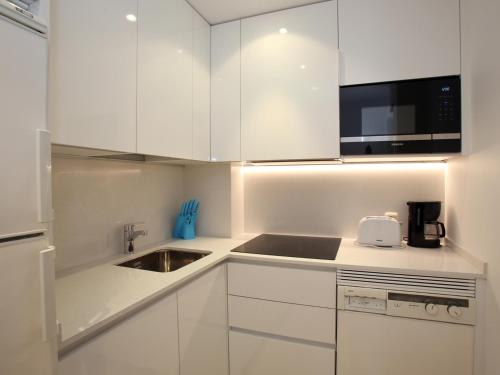 una cocina blanca con armarios blancos y fregadero en Orly, en San Sebastián