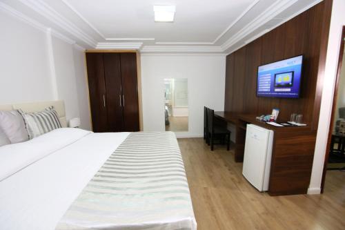 a bedroom with a bed and a desk and a television at Laguna Plaza Hotel in Brasilia