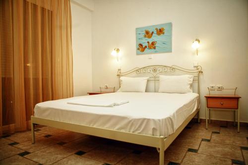 een slaapkamer met een groot bed met witte lakens en kussens bij Chrouso Apartments in Paliouri