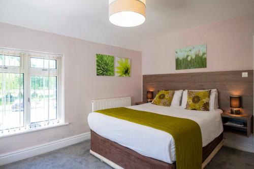a bedroom with a large bed and two windows at The Limes Country Lodge Hotel & Admiral Restaurant in Solihull