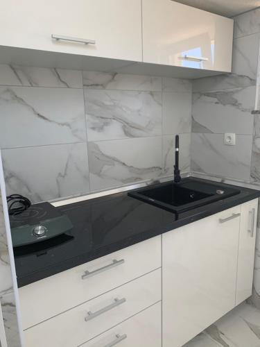 a kitchen with white cabinets and a black counter top at Apartments Albatross in Novalja