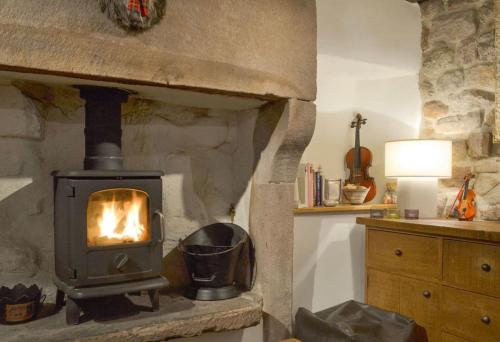 a stone fireplace in a room with a stove at Little Cottage in Cromford