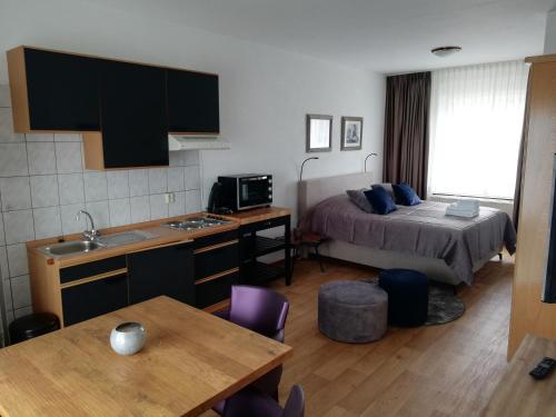 a room with a bed and a kitchen with a table at Bellevue appartementen in Simpelveld