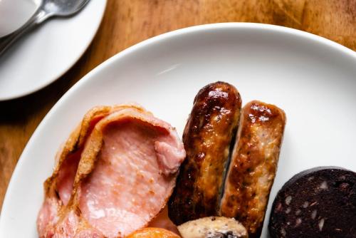 a white plate with meat and sausages on a table at The Limes Country Lodge Hotel & Admiral Restaurant in Solihull