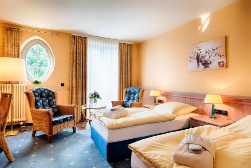 ハルバーシュタットにあるHotel Villa Heine Wellness & Spaのベッド2台、テーブルと椅子が備わるホテルルームです。