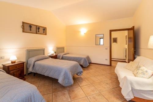a hotel room with three beds and a couch at Agriturismo La Fonte in Bevagna