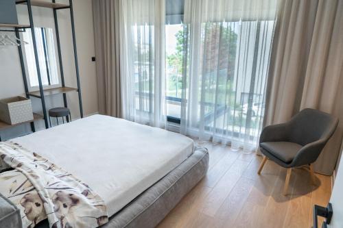 a bedroom with a bed and a chair and window at Buena Vista Villas in Varna City