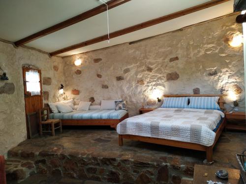 sypialnia z 2 łóżkami i kamienną ścianą w obiekcie Wellanidia Cottage Skoutari w mieście Gythio
