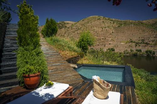 a wooden deck with a swimming pool next to a river at Casa do Rio - Douro Wine Hotel by Vallado in Vila Nova de Foz Coa
