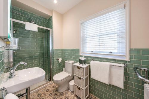 a green tiled bathroom with a toilet and a sink at Eight in Bath